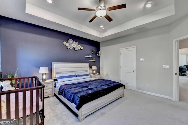 carpeted bedroom featuring a tray ceiling and ceiling fan