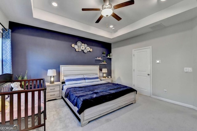 bedroom with a tray ceiling, ceiling fan, and light colored carpet