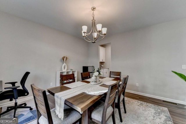 dining space with hardwood / wood-style floors and an inviting chandelier