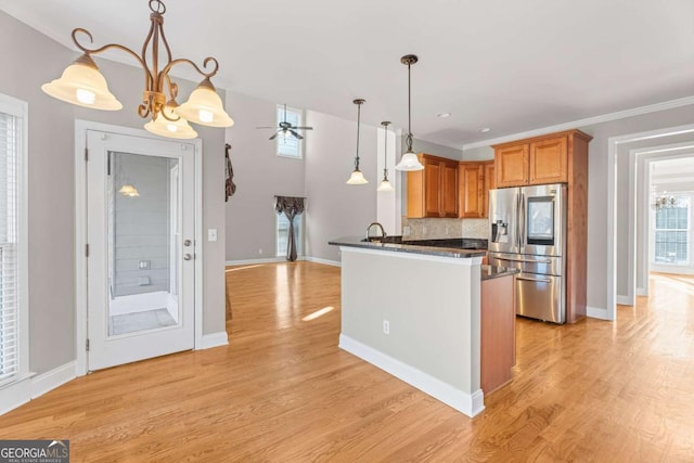 kitchen featuring tasteful backsplash, pendant lighting, stainless steel refrigerator with ice dispenser, and light wood-type flooring