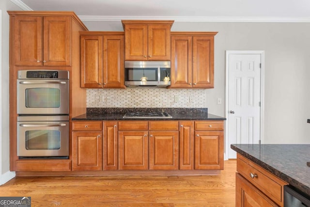 kitchen featuring dark stone countertops, ornamental molding, tasteful backsplash, light hardwood / wood-style floors, and stainless steel appliances