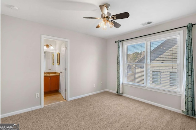 unfurnished bedroom featuring ensuite bathroom, ceiling fan, light colored carpet, and sink