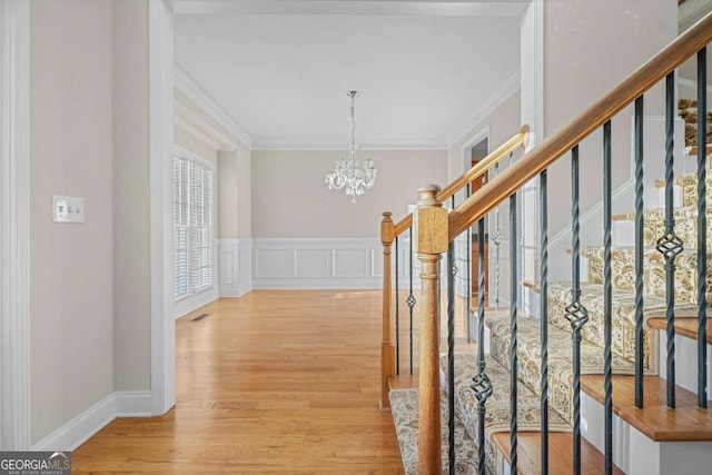 hall with light hardwood / wood-style flooring, a chandelier, and ornamental molding