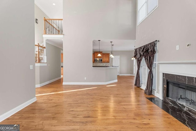 unfurnished living room featuring light hardwood / wood-style floors, a premium fireplace, and crown molding