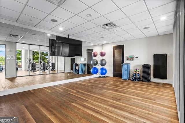 exercise room with a drop ceiling and wood-type flooring