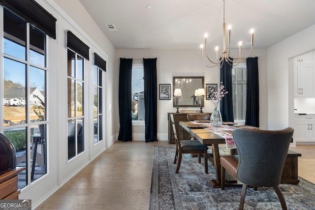 dining area with french doors, hardwood / wood-style floors, and a notable chandelier