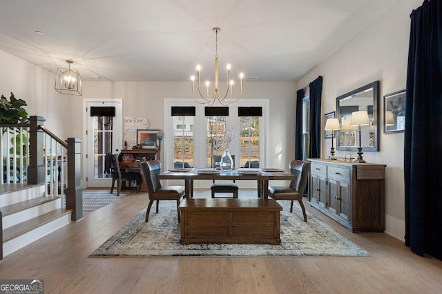 dining area with light hardwood / wood-style flooring and a notable chandelier