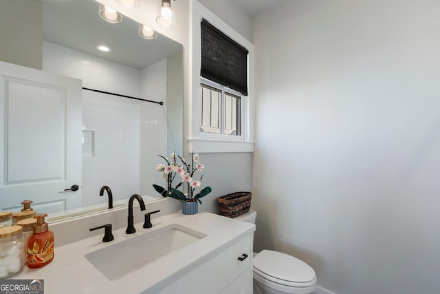 bathroom featuring toilet, vanity, and walk in shower