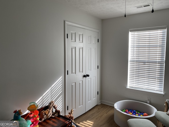 rec room featuring a textured ceiling, hardwood / wood-style flooring, and plenty of natural light