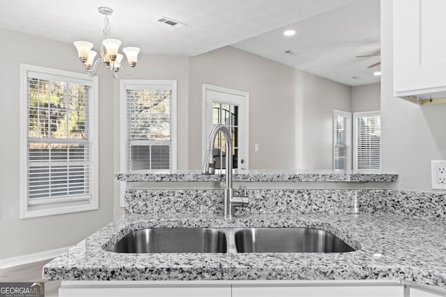 kitchen with sink, hanging light fixtures, plenty of natural light, white cabinets, and ceiling fan with notable chandelier