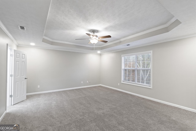 empty room featuring ceiling fan, ornamental molding, carpet floors, and a tray ceiling