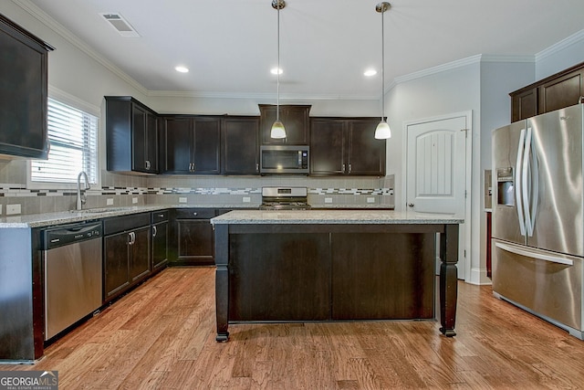 kitchen with decorative light fixtures, a kitchen island, dark brown cabinetry, and appliances with stainless steel finishes