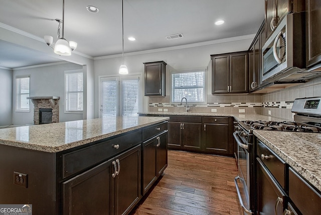 kitchen featuring dark hardwood / wood-style flooring, stainless steel appliances, an inviting chandelier, a center island, and hanging light fixtures