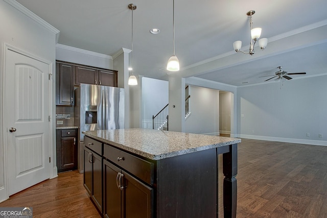 kitchen featuring dark brown cabinets, a kitchen island, hanging light fixtures, and ornamental molding