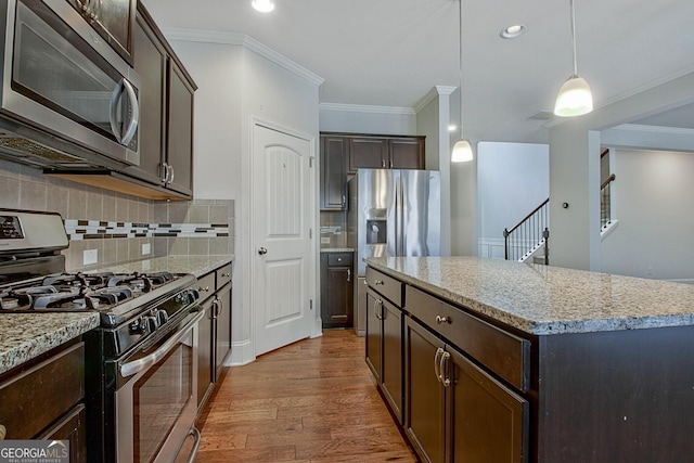 kitchen featuring a center island, crown molding, hanging light fixtures, tasteful backsplash, and stainless steel appliances