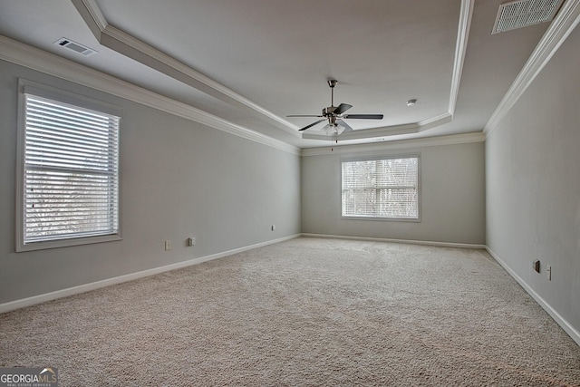 carpeted empty room featuring ceiling fan, a raised ceiling, and crown molding