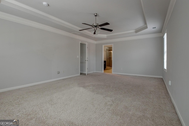 empty room with a tray ceiling, ceiling fan, light carpet, and ornamental molding