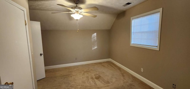 additional living space featuring a textured ceiling, ceiling fan, light colored carpet, and lofted ceiling