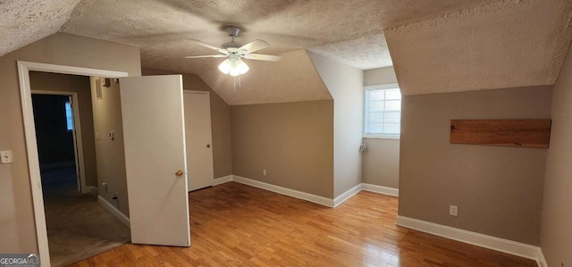 additional living space featuring ceiling fan, light wood-type flooring, lofted ceiling, and a textured ceiling