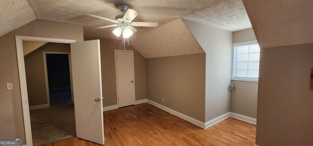 additional living space featuring hardwood / wood-style flooring, ceiling fan, lofted ceiling, and a textured ceiling