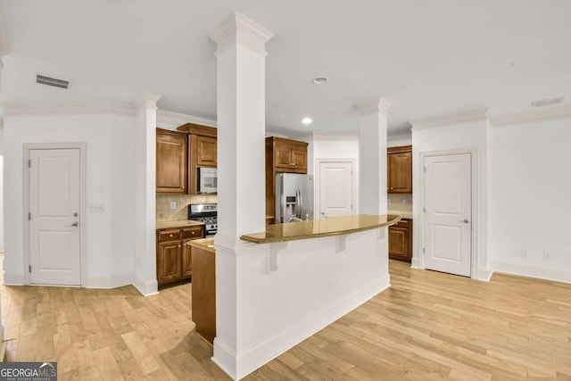 kitchen with a breakfast bar, a center island, ornamental molding, stainless steel appliances, and decorative columns