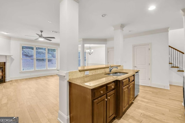 kitchen with dishwasher, sink, light stone counters, crown molding, and ceiling fan with notable chandelier