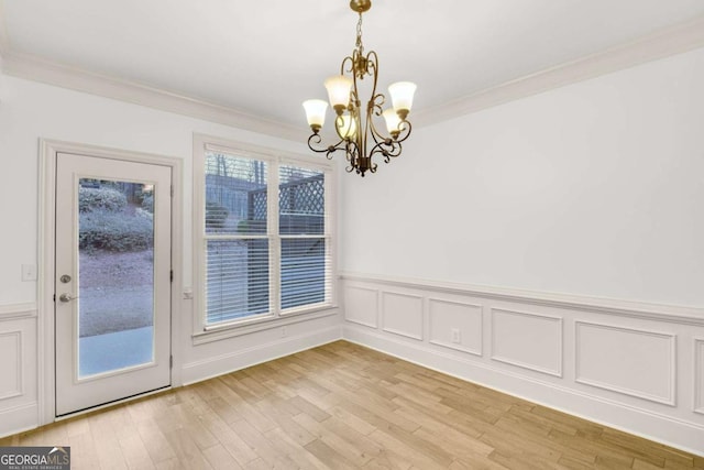 unfurnished dining area with a chandelier, light hardwood / wood-style flooring, and crown molding