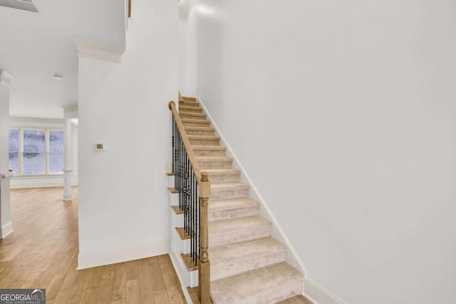 staircase with hardwood / wood-style flooring and crown molding