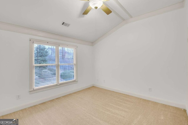 empty room with vaulted ceiling with beams, ceiling fan, light colored carpet, and crown molding