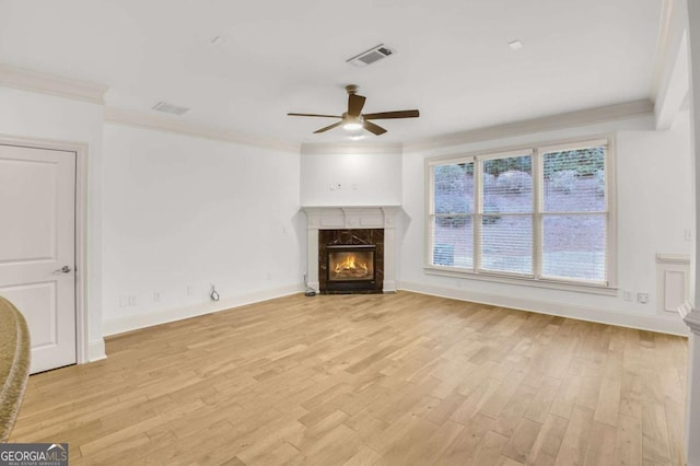 unfurnished living room featuring ceiling fan, a fireplace, crown molding, and light hardwood / wood-style flooring