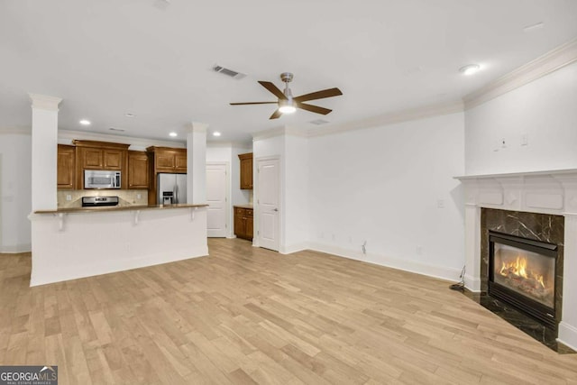 unfurnished living room featuring crown molding, a high end fireplace, light hardwood / wood-style floors, and ceiling fan