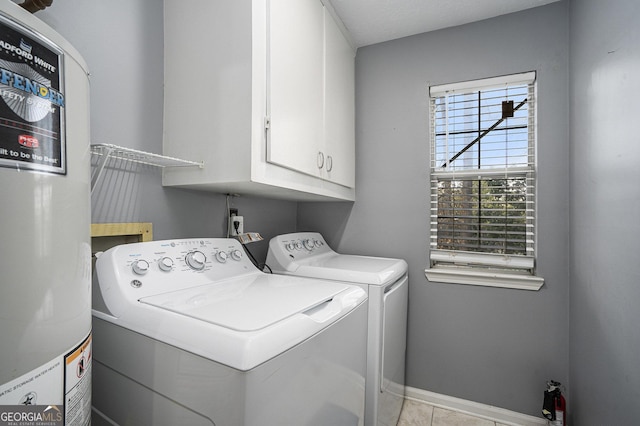 laundry area featuring cabinets, light tile patterned floors, water heater, and independent washer and dryer