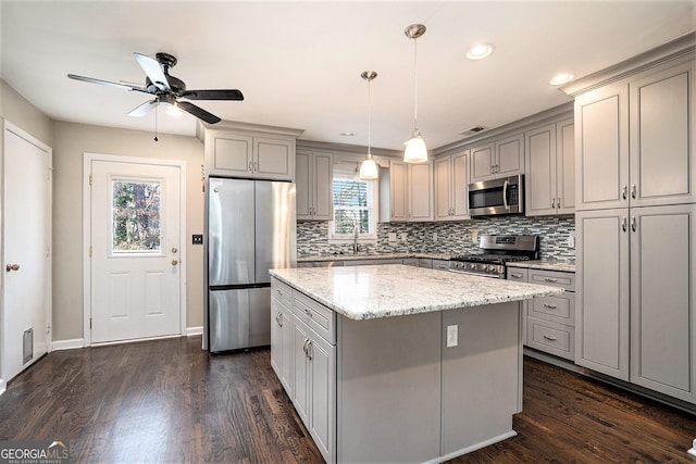 kitchen featuring gray cabinetry, decorative light fixtures, stainless steel appliances, and a center island