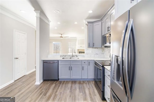 kitchen with crown molding, sink, ceiling fan, light wood-type flooring, and appliances with stainless steel finishes