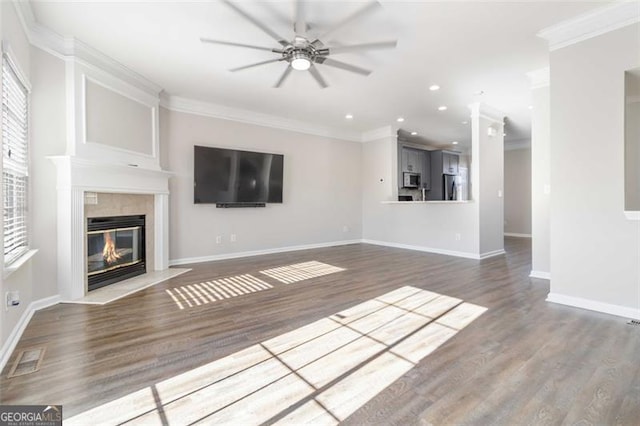 unfurnished living room featuring hardwood / wood-style floors, ceiling fan, ornamental molding, and a fireplace