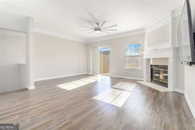 unfurnished living room with a tiled fireplace, crown molding, ceiling fan, and hardwood / wood-style flooring