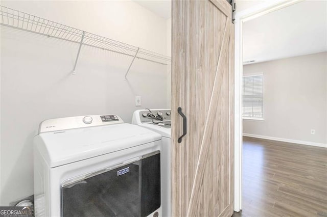 washroom with a barn door, washer and clothes dryer, and hardwood / wood-style floors