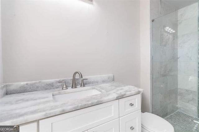 bathroom with a tile shower, vanity, and toilet