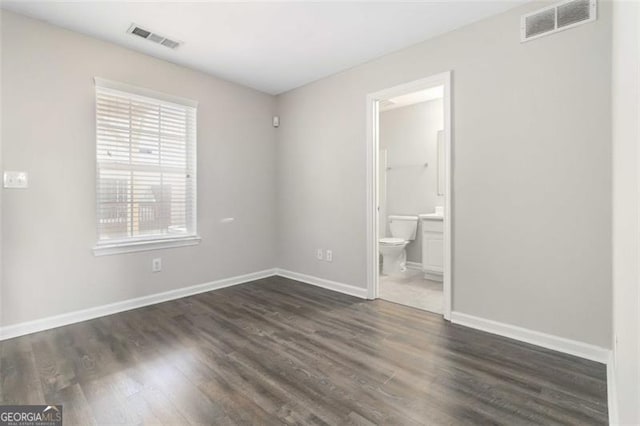 unfurnished bedroom with dark wood-type flooring and connected bathroom