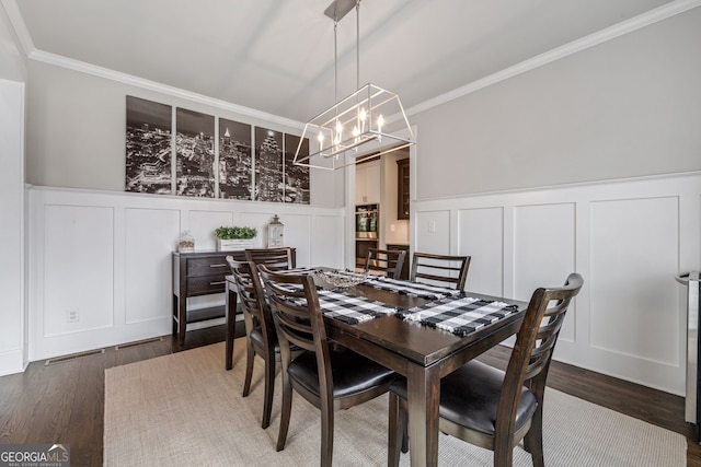 dining area with dark hardwood / wood-style flooring, a chandelier, and ornamental molding