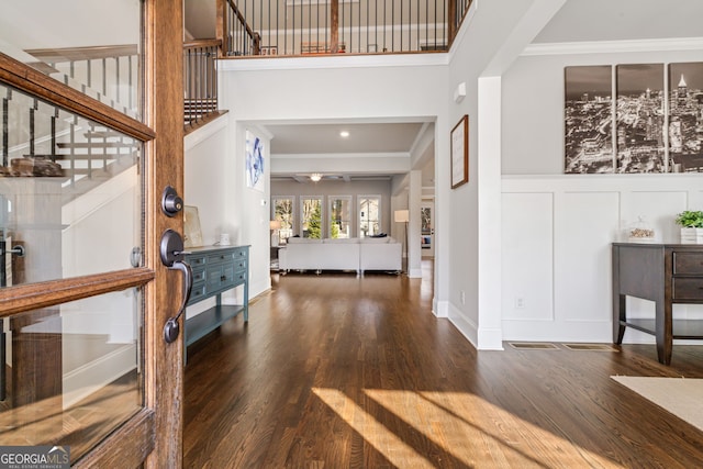 entryway with ornamental molding and dark wood-type flooring