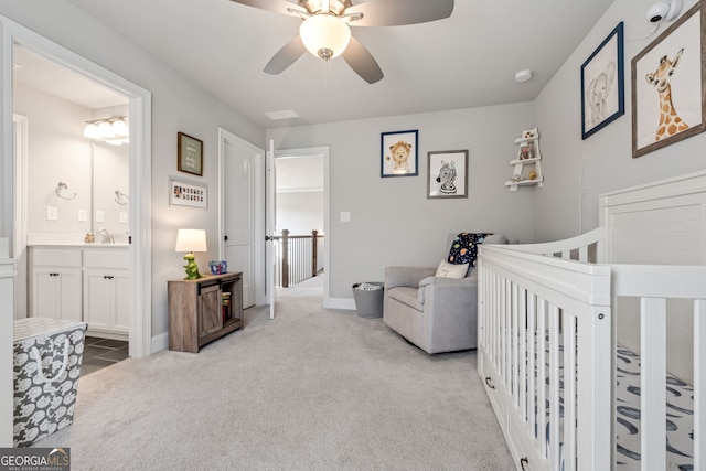 carpeted bedroom featuring ceiling fan, connected bathroom, a crib, and sink