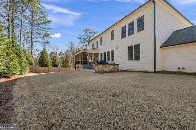 rear view of house featuring a yard, a sunroom, and a patio area