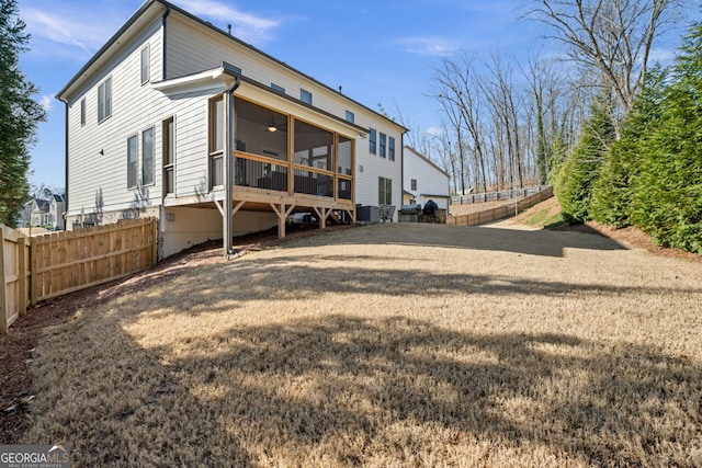 rear view of property with ceiling fan, a lawn, and a sunroom