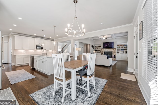 dining room featuring sink, a fireplace, ornamental molding, dark hardwood / wood-style flooring, and built in shelves