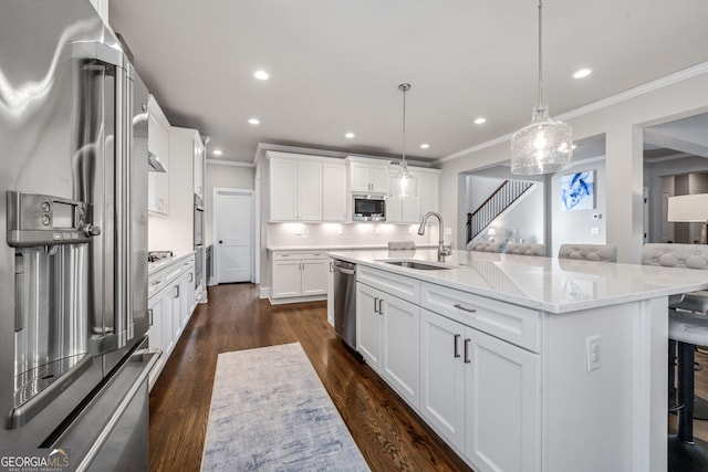 kitchen with hanging light fixtures, white cabinets, appliances with stainless steel finishes, a kitchen breakfast bar, and sink