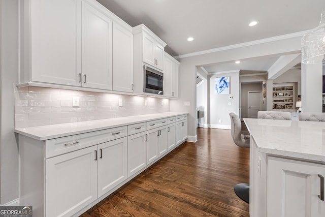 kitchen featuring white cabinets, tasteful backsplash, light stone countertops, dark hardwood / wood-style floors, and built in microwave