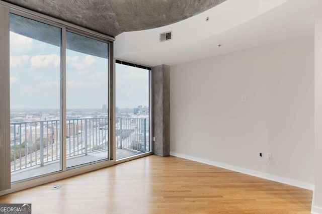 spare room with hardwood / wood-style floors, a healthy amount of sunlight, and a wall of windows