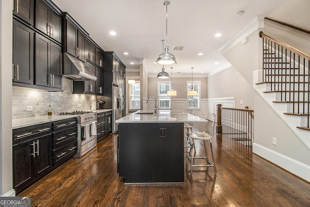 kitchen with a breakfast bar, hanging light fixtures, ornamental molding, stainless steel appliances, and a center island with sink