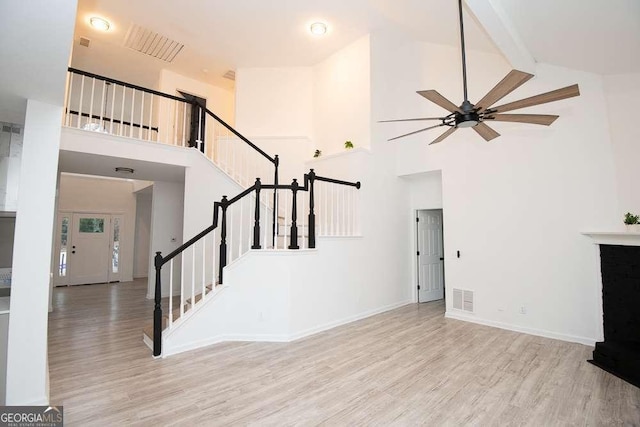 unfurnished living room featuring ceiling fan, high vaulted ceiling, and light wood-type flooring